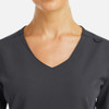 A women's dark grey V-neck top featuring a metallic detail and a logo on the shoulder.