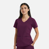 A women's V-neck top in deep plum, featuring metallic detail and front pockets. The model showcases the top's fit and style.
