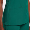 A green women's mock wrap top featuring two front pockets and a smooth finish. It has a logo on the fabric.