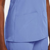 A women's mock wrap top in light blue, featuring two front pockets and a smooth fabric. It has a logo displayed.