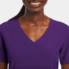 A mock wrap top in a vibrant purple hue, featuring a V-neck and short sleeves, with a logo present.