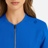 A blue women's full zip bomber jacket with a round neckline and a shoulder tab. There is a logo on the jacket.