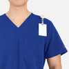 A blue V-neck top featuring contrast piping, a pocket, and a clip-on badge holder.