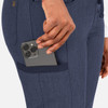A close-up of a hand placing a smartphone into a navy tapered pant pocket. The pants feature a sleek design.