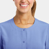 A round neck snap jacket in light blue with a button closure at the neck, featuring a logo on the fabric.