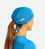 A unisex scrub cap in vibrant blue, designed with a ponytail opening at the back. Features a logo tag.