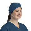 A unisex scrub cap in navy blue, featuring buttons, worn by a smiling woman with a ponytail.