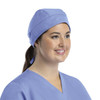 A unisex scrub cap in light blue with buttons, worn by a smiling woman, featuring a stylish design.