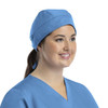 A unisex scrub cap in light blue with buttons, worn by a smiling woman.
