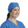 A unisex scrub cap in blue, featuring buttons and worn by a smiling individual.
