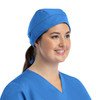 A unisex blue scrub cap with buttons, worn by a woman smiling, set against a plain background.