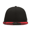 A black snapback cap with a structured high profile and a red plaid bill. Features a logo on the underside of the bill.