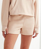 A pair of beige jogger shorts with a relaxed fit, featuring side pockets and a smooth fabric finish.