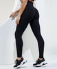 Black recycled scrunch leggings are displayed from the back, paired with black athletic shoes. The image features a logo.