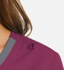 A close-up of a women's mock wrap top in a deep purple shade with grey contrast trim and a decorative detail on the shoulder.