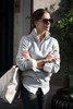 A grey unisex sweatshirt with a half-zip collar, worn by a person with sunglasses, carrying a large bag.