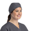 A grey cap with a button, worn by a smiling woman in a grey top, showcasing a stylish design.