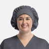 A grey bouffant cap worn by a smiling person, featuring a gathered design and a smooth band.