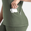 A green banded V-neck top featuring side pockets, one holding a phone and another with a pen. It has a logo.