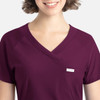 A purple Y-neck top featuring a pocket and a logo, designed for a comfortable fit.