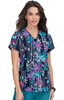 A floral print scrub top featuring a navy background with vibrant purple, pink, and white patterns. It has a logo.