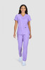 A woman wearing a lavender scrubs set, featuring a V-neck top and matching pants, with a logo visible.