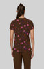 A floral print top in brown, featuring pink and purple flowers, viewed from the back on a model.