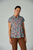 Ari Top (Print) featuring a blue patterned fabric with floral and animal designs, paired with brown pants.