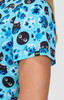 A top featuring a blue floral print with black circular designs and faces, showcasing vibrant shades of blue. It has a logo.