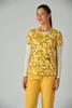 A floral print top in yellow and white, worn with long sleeves, paired with yellow trousers. Features a brand logo.