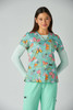 A woman models the Leslie Top in a vibrant print featuring butterflies, with a mint green background and matching trousers.