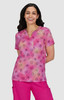 A patterned pink top featuring a V-neck and short sleeves, worn by a smiling woman.