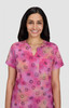 A pink short-sleeve top featuring a pattern of various smiley faces, with a relaxed neckline and a light fabric.