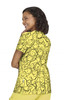 A vibrant yellow T-shirt featuring a playful pattern of smiling faces. The model is shown from the back and has curly hair.