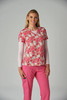 A pink patterned top featuring colourful designs, worn over a long-sleeve shirt, paired with pink pants.