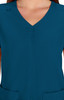 A teal medical scrub top featuring a V-neck design and gathered detailing at the front. It has pockets and a logo.