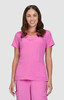 A pink scrubs top featuring a V-neck design and two front pockets, modelled by a smiling woman.