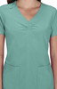 A scrub top in a teal colour with a V-neck and short sleeves, featuring two front pockets and a logo.