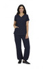 A woman stands wearing navy scrubs with a V-neck top and relaxed fit pants. The outfit includes pockets and has a logo.
