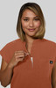A woman with shoulder-length hair models an orange top with a zippered neckline and a logo.