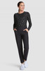 A black long-sleeve top with a patterned design, paired with black trousers and white shoes. The model stands with hands in pockets.