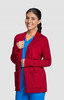 A red Kori Sweater featuring two front pockets, styled with a blue top, modelled by a smiling woman.