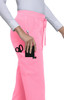 A pair of pink jogger pants with pockets, one holding scissors and a phone. The pants have a logo.