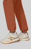 Wide leg pants in a rich terracotta hue, paired with cream and beige sneakers, displayed against a neutral background.