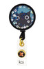 A round badge with a black cat design, surrounded by colourful sequins and flowers, featuring a hook for attachment.
