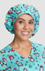 A bouffant scrub cap in light blue featuring a penguin pattern, worn by a smiling woman.