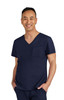 A navy blue scrubs top featuring a V-neck and a chest pocket. The model is smiling and wearing matching scrubs pants.