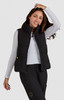 A woman models a black padded vest over a long-sleeve white top, smiling and posing against a plain background.