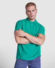A green Austral Polo Shirt worn by a model with short hair, standing with arms crossed. The shirt has a collar and features a logo.