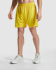 Yellow sports shorts with an elastic waistband, worn by a model alongside white athletic shoes.
